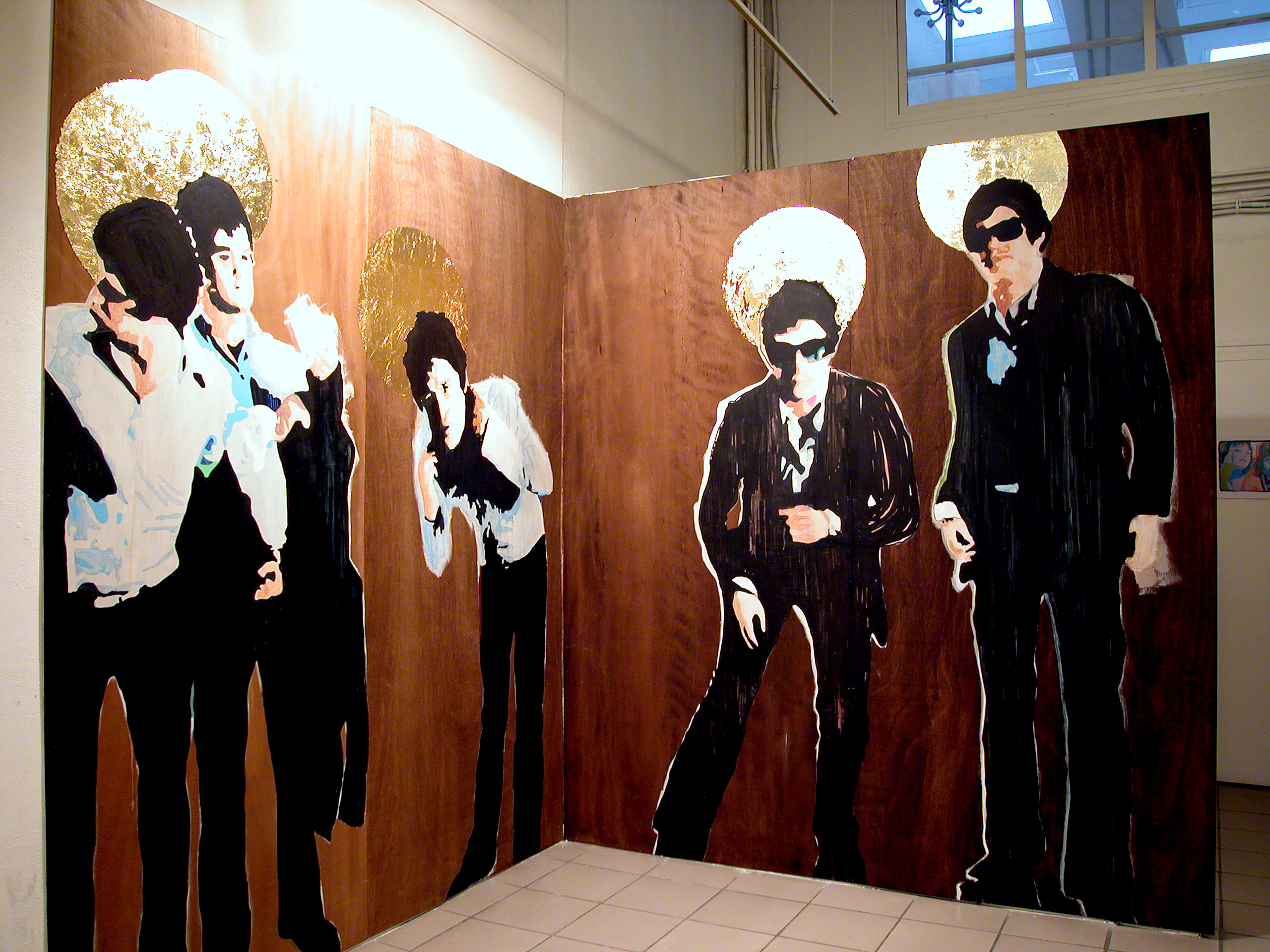 Gallery installation of folding painted panels showing four formally dressed figures with gold halos against a dark red ground.